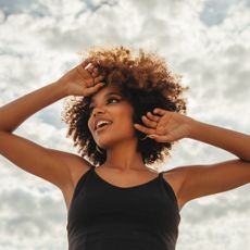 Best vitamin C serum: woman shielding face from sun with her hand