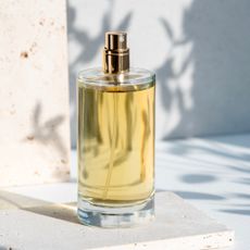 Sunlit glass bottle of yellow perfume