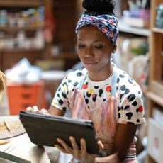 A woman sits using her tech for craft