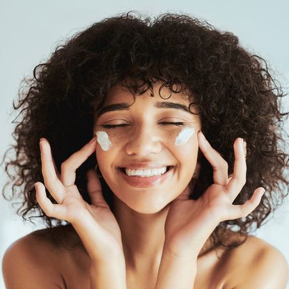 image of a smiling woman with cream on her cheeks - Best moisturiser