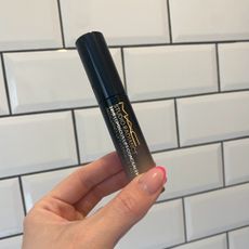 Original image showing a hand holding the MAC Studio Radiance Concealer against a white tiled background 